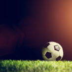 Football soccer ball on grass in spotlight. Sport